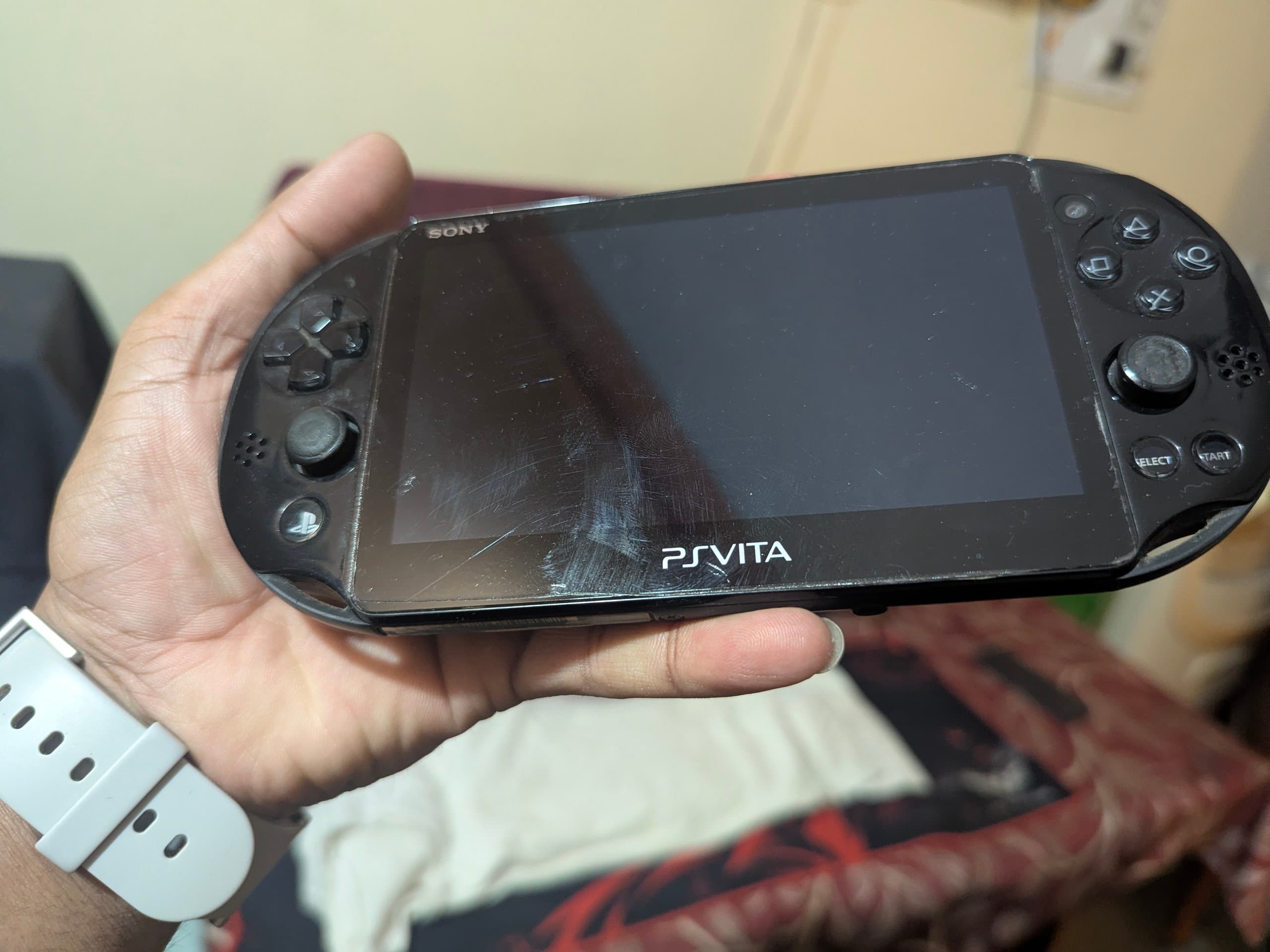 A PS Vita Slim handheld console held by the owner, showing the device in 2026